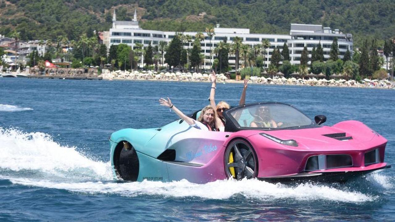 Muğla'nın Bodrum ilçesinde sıcak havadan bunalan tatilcilerin araçlarıyla denize girmesi.