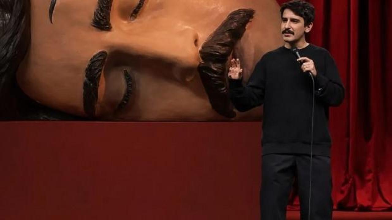Sahne ışıkları altında mikrofon başında bir komedyen