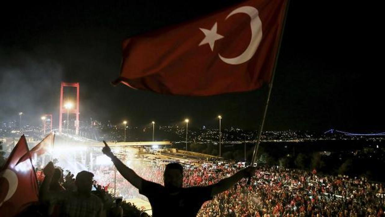 Türk bayrağı ve 15 Temmuz şehitlerini anan kalabalık görseli.