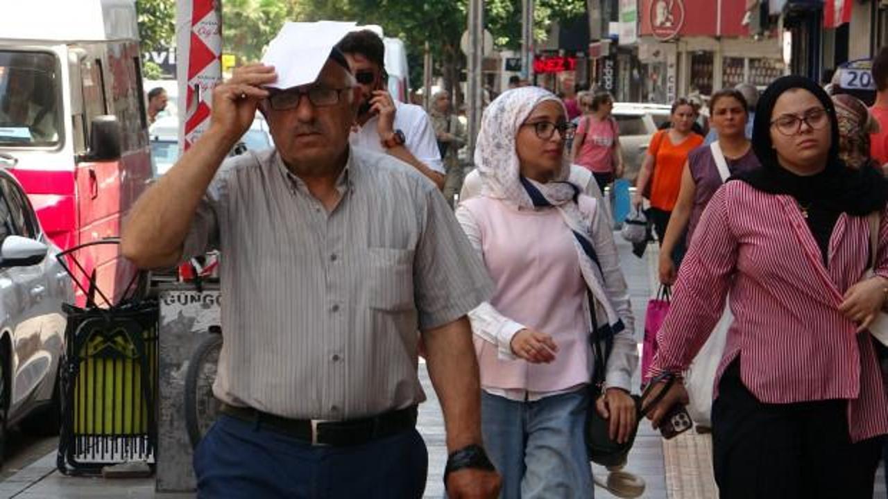 Sıcak havada serinlemek için sahilde oturan insanlar