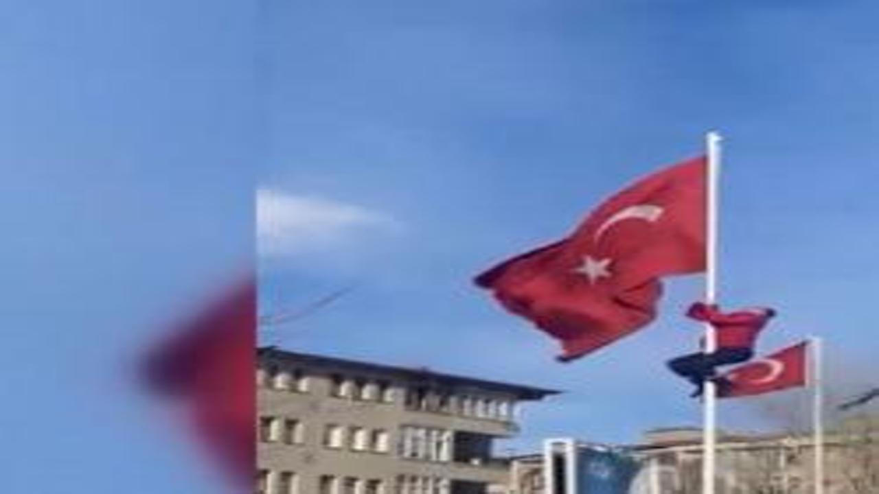 Rüzgarda dolanan bayrağı düzeltmek için direğe tırmanan çalışan gönüllerl fethetti